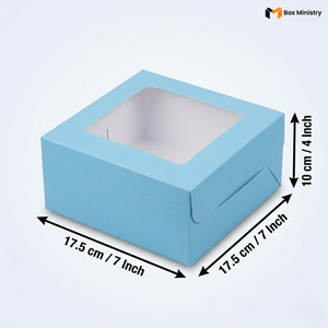 Sky blue square window cake box with clear PVC lid window, dimensions 17.5 x 17.5 x 10 cm (7 x 7 x 4 inches), shown in 3/4 isometric angle with measurement arrows, white interior lining visible through window, on a soft light blue-white gradient background