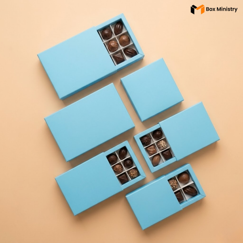 Set of blue chocolate boxes with chocolates on a beige background, featuring the Box Ministry logo.
