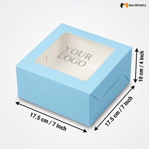 Soft sky blue square cake box with large square clear PVC window on lid showing "YOUR LOGO" text in elegant serif grey font on white interior base, dimensions 17.5 x 17.5 x 10 cm (7 x 7 x 4 inches), shown in 3/4 isometric angle with bold black measurement arrows on right and bottom edges, visible tuck-lock flap on right side face, matte finish, on a soft dark grey-white gradient background