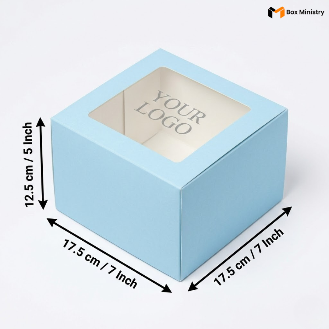 Soft sky blue square cake box with large square clear PVC window on lid showing "YOUR LOGO" text in elegant serif grey font on white interior base, dimensions 17.5 x 17.5 x 12.5 cm (7 x 7 x 5 inches), shown in 3/4 isometric angle with bold black measurement arrows on left and bottom edges, visible tuck-lock flap on right side face, matte finish, on a soft pure white background

