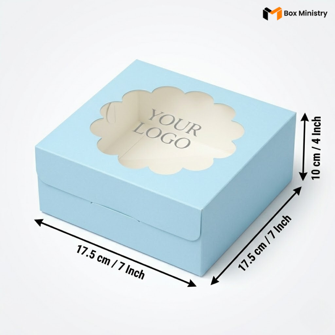 Soft sky blue square cake box with ornate flower-shaped scalloped petal PVC window showing "YOUR LOGO" text in elegant serif grey font, dimensions 17.5 x 17.5 x 10 cm (7 x 7 x 4 inches), shown in 3/4 isometric angle with bold black measurement arrows, visible side lock closure on front face, matte finish, on a soft light grey-white gradient background