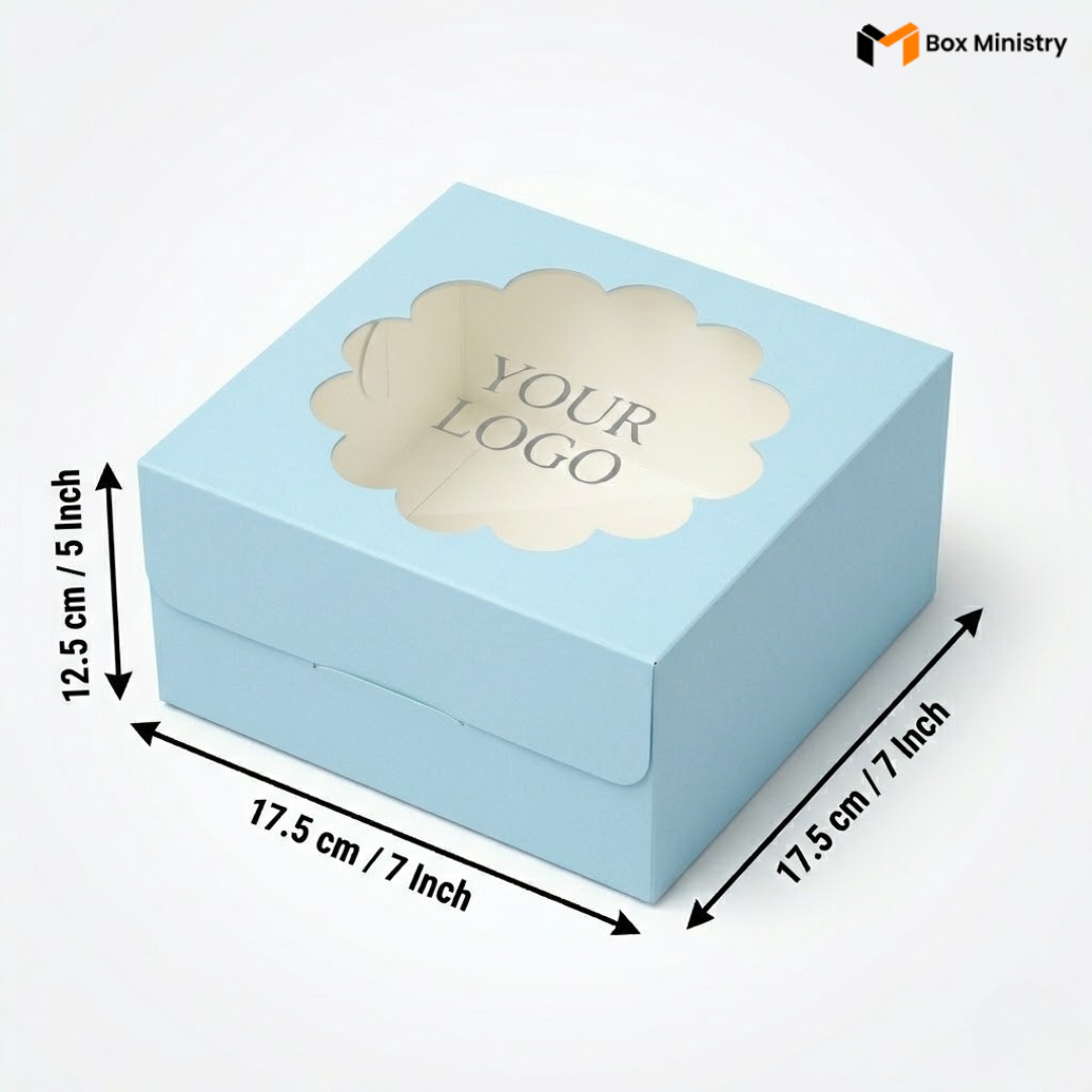 Soft sky blue square cake box with ornate flower-shaped scalloped petal PVC window showing "YOUR LOGO" text in elegant serif grey font, dimensions 17.5 x 17.5 x 12.5 cm (7 x 7 x 5 inches), shown in 3/4 isometric angle with bold black measurement arrows, visible side lock closure on front face, matte finish, on a soft light grey-white gradient background