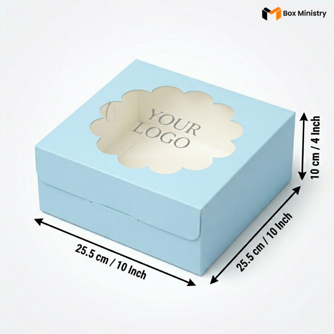 Soft sky blue square cake box with ornate flower-shaped scalloped petal PVC window showing "YOUR LOGO" text in elegant serif grey font, dimensions 25.5 x 25.5 x 10 cm (10 x 10 x 4 inches), shown in 3/4 isometric angle with bold black measurement arrows, visible side lock closure on front face, matte finish, on a soft light grey-white gradient background
