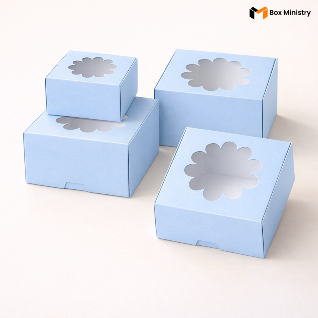 Four sky blue flower window cake boxes in two sizes arranged in a stacked tower layout on a soft cream background — small box stacked on top of large box on the left, two medium boxes on the right — Blue Flower Window Cake Boxes .