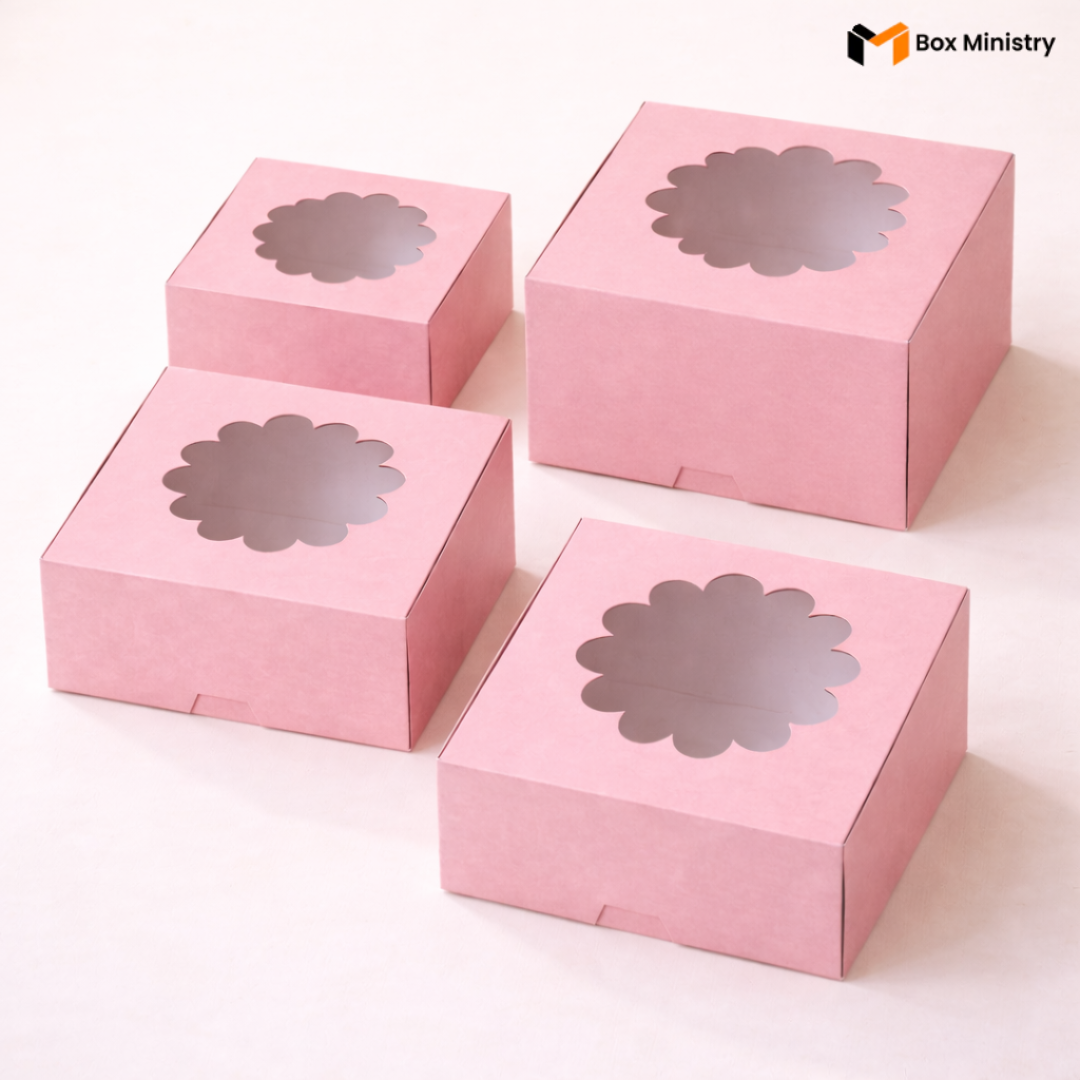 Four pink flower window cake boxes arranged in a 2x2 grid on a soft white background — each box features a decorative circular flower-shaped PVC window on the lid with scallop petal edges — Pink Flower Window Cake Boxes