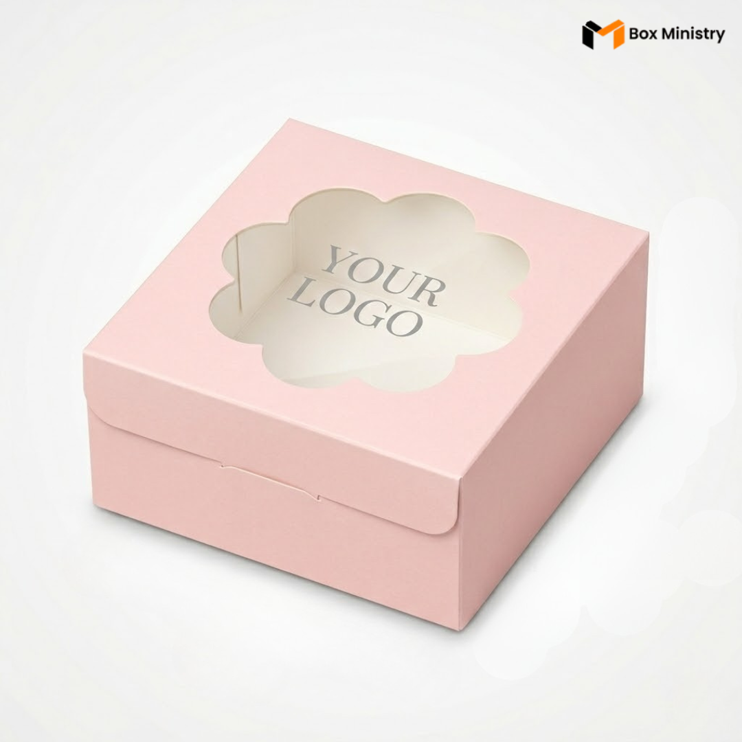 
Soft blush pink square cake box with large square clear PVC window on lid showing "YOUR LOGO" text in elegant serif dark charcoal font centered on white interior base, positioned at 3/4 isometric angle, visible tuck-lock flap on right side face, tall upright shape with prominently visible side walls, matte finish, on a soft pale pink to warm white gradient background


