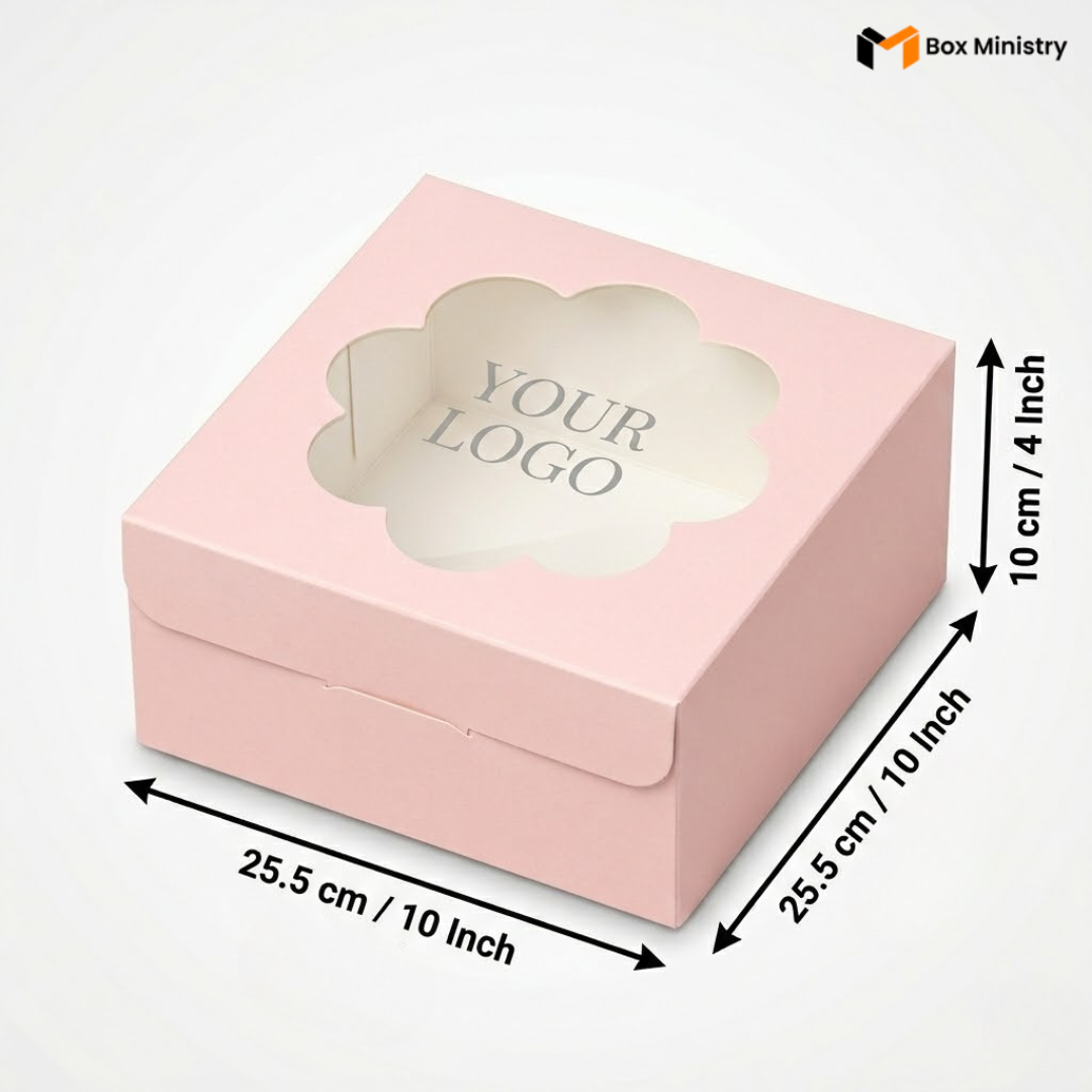 Soft blush pink square cake box with ornate flower-shaped scalloped petal PVC window showing "YOUR LOGO" text in elegant serif grey font on white interior base, dimensions 25.5 x 25.5 x 10 cm (10 x 10 x 4 inches), shown in 3/4 isometric angle with bold black measurement arrows on right and bottom edges, visible side lock closure on front face, flat matte pink finish, on a soft pure white background