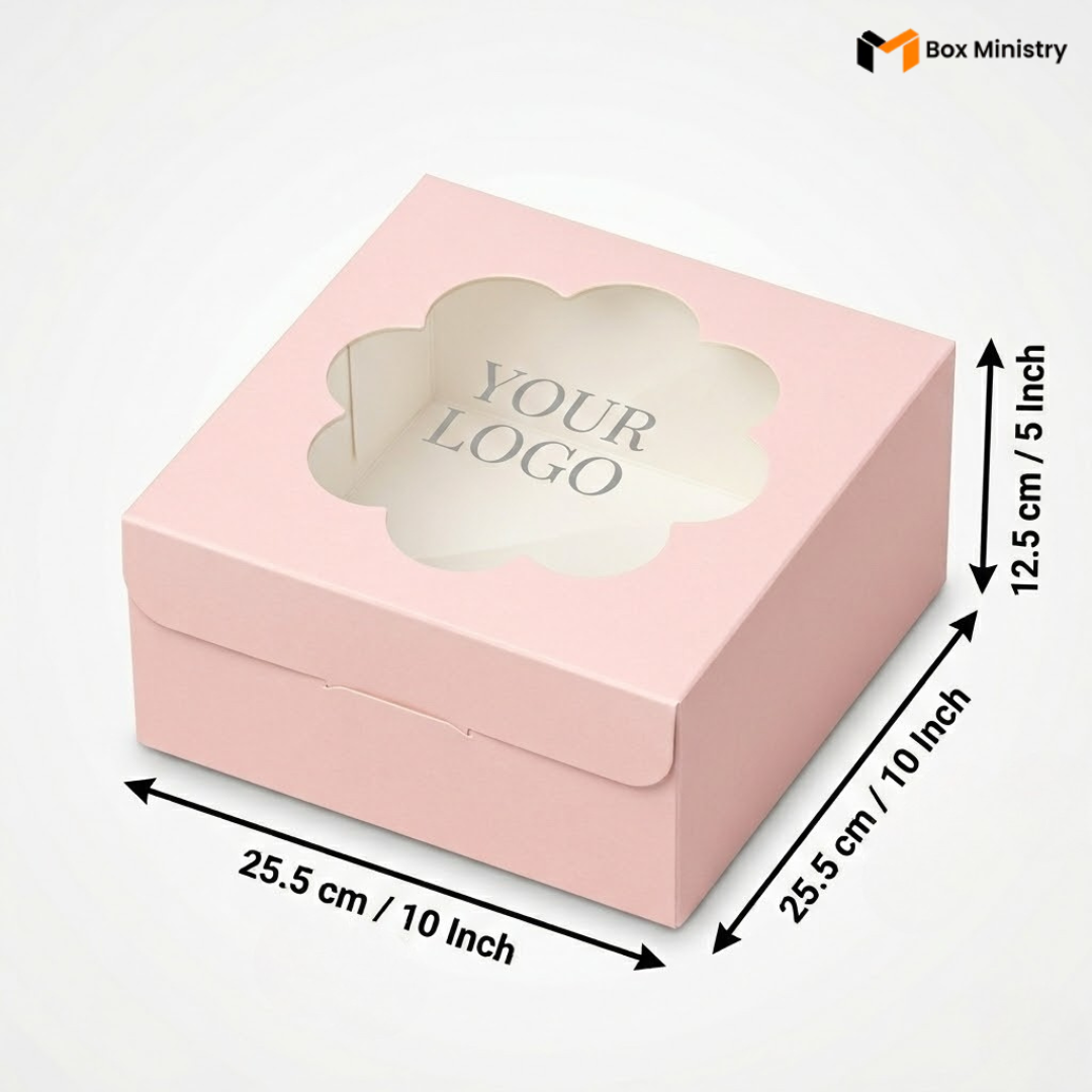 Soft blush pink square cake box with ornate flower-shaped scalloped petal PVC window showing "YOUR LOGO" text in elegant serif grey font on white interior base, dimensions 25.5 x 25.5 x 12.5 cm (10 x 10 x 5 inches), shown in 3/4 isometric angle with bold black measurement arrows on right and bottom edges, visible side lock closure on front face, flat matte pink finish, on a soft pure white background