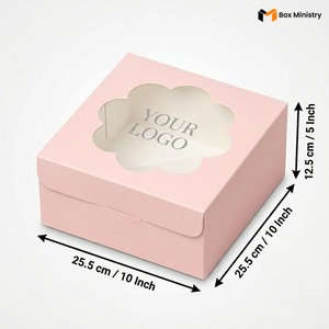 Soft blush pink square cake box with ornate flower-shaped scalloped petal PVC window showing "YOUR LOGO" text in elegant serif grey font on white interior base, dimensions 25.5 x 25.5 x 12.5 cm (10 x 10 x 5 inches), shown in 3/4 isometric angle with bold black measurement arrows on right and bottom edges, visible side lock closure on front face, flat matte pink finish, on a soft pure white background