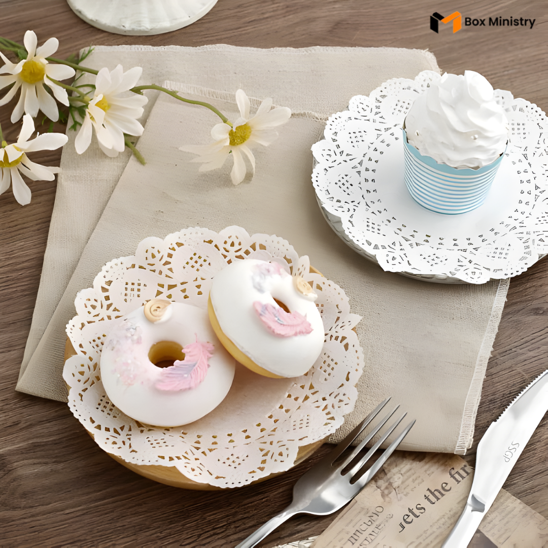 Decorative donuts with animal faces on a lace doily with flowers and a cupcake in the background.